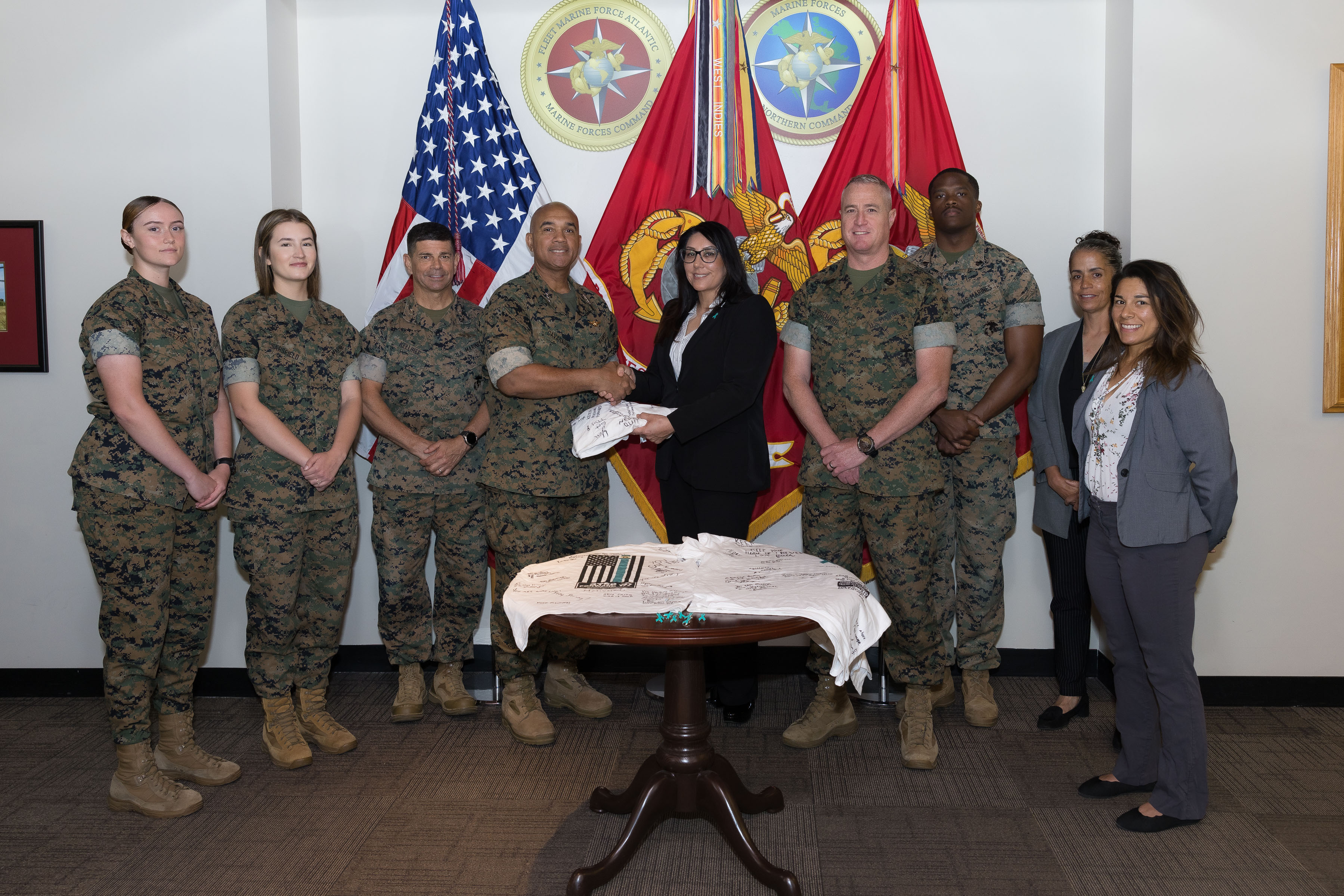 U.S Marine Corps Lt. Gen. Brian W. Cavanaugh, commander, Fleet Marine Force, Atlantic, Marine Forces Command; commanding general, Marine Forces Northern Command, center left, is presented a signed commemorative t-shirt by Ms. Christina Chavez, MARFORCOM Supervisory Sexual Assault Response Coordinator, center right, in honor of Sexual Assault Awareness and Prevention Month (SAAPM) at MARFORCOM headquarters on Naval Support Activity Hampton Roads, Virginia, May 5, 2023. During the signing ceremony, MARFORCOM leadership expressed their support for the 2023 SAAPM advocacy campaign and call-to-action theme: "STEP FORWARD. Prevent. Report. Advocate." Every April, SAAPM highlights how sexual harassment, sexual assault, and sexual abuse impact every person in the community. By raising public awareness SAAPM aims to educate communities on how to prevent sexual violence. (U.S. Marine Corps photo by Casey Price)